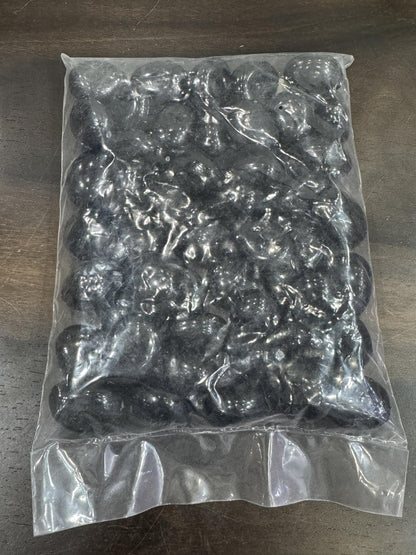 Clear plastic bag filled with black pebbles on a wooden surface