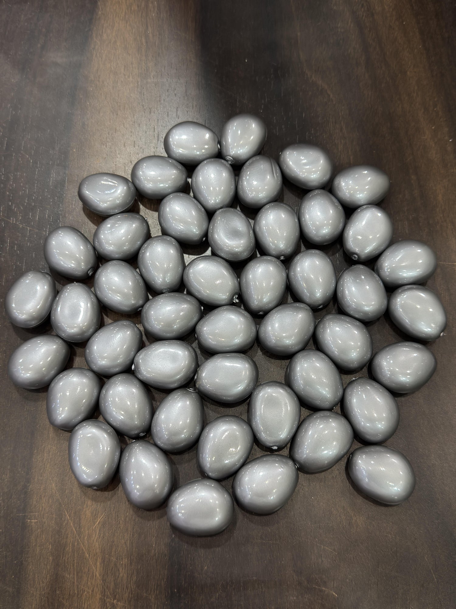 Gray teardrop-shaped beads on a wooden surface