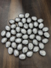Gray teardrop-shaped beads on a wooden surface