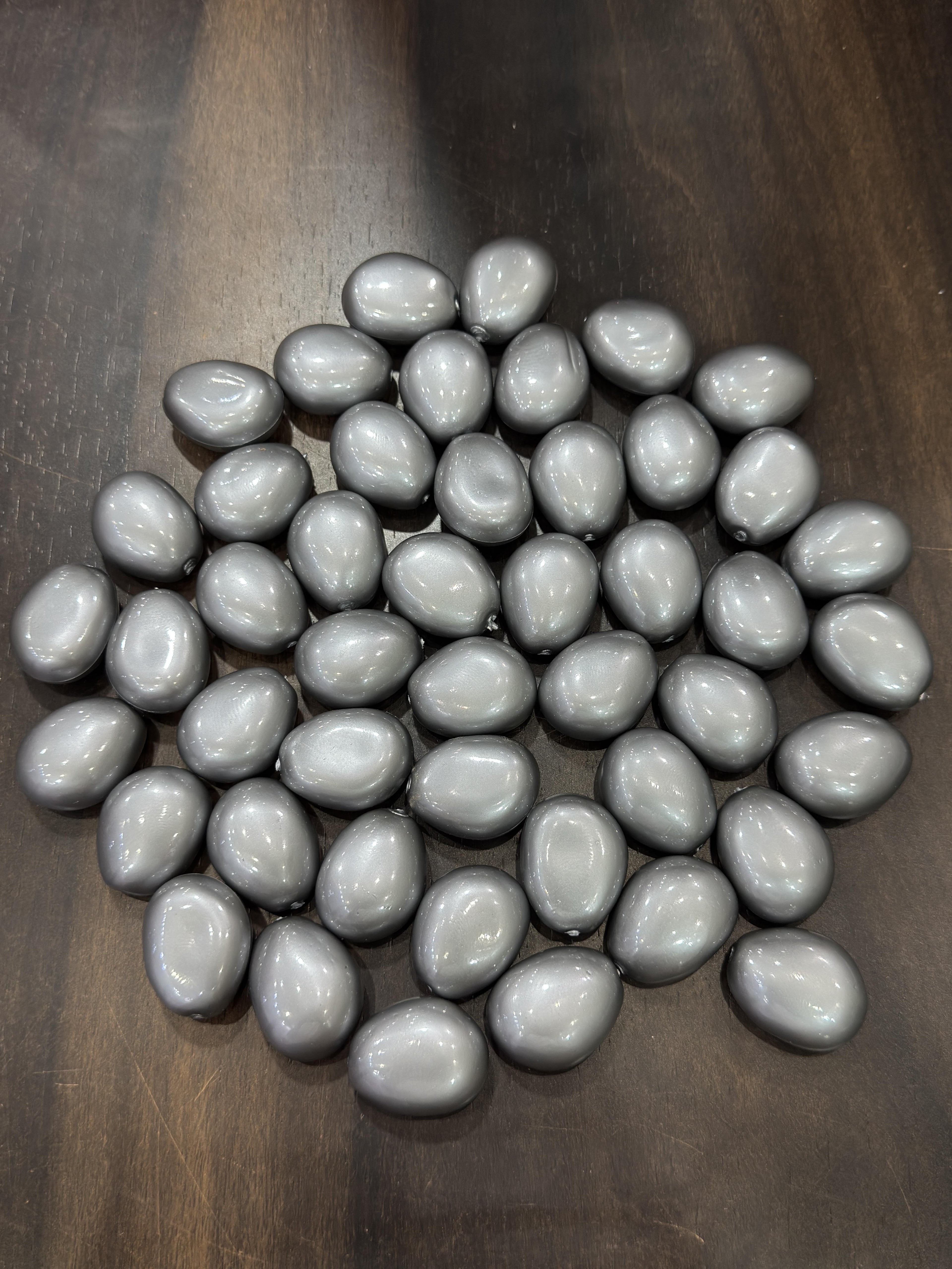 Gray teardrop-shaped beads on a wooden surface