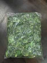 Clear plastic bag filled with green beads on a dark surface