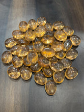 Collection of transparent amber-colored glass marbles on a dark surface