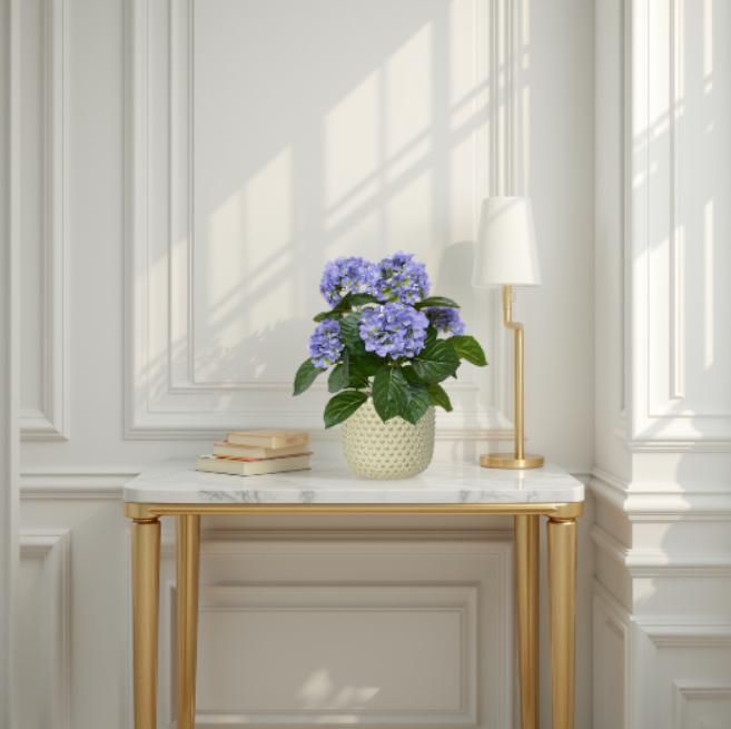 Decorative table with a vase of purple flowers and a lamp in a room with white walls and gold accents.