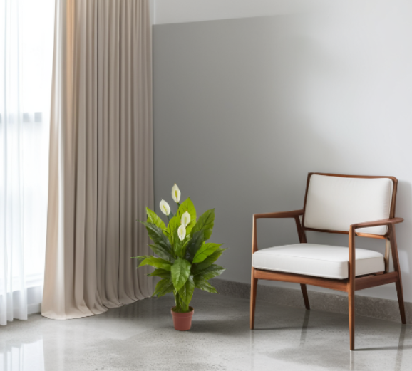 Modern chair with white cushion next to a potted plant in a room with gray walls and beige curtains.