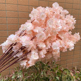 Bouquet of pink artificial cherry blossom flowers against a beige tiled wall