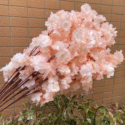 Bouquet of pink artificial cherry blossom flowers against a beige tiled wall