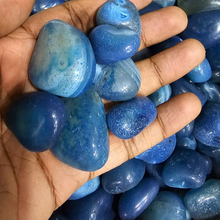 Hand holding blue stones with a background of more blue stones