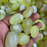 Hand holding green pebbles with a background of more green stones