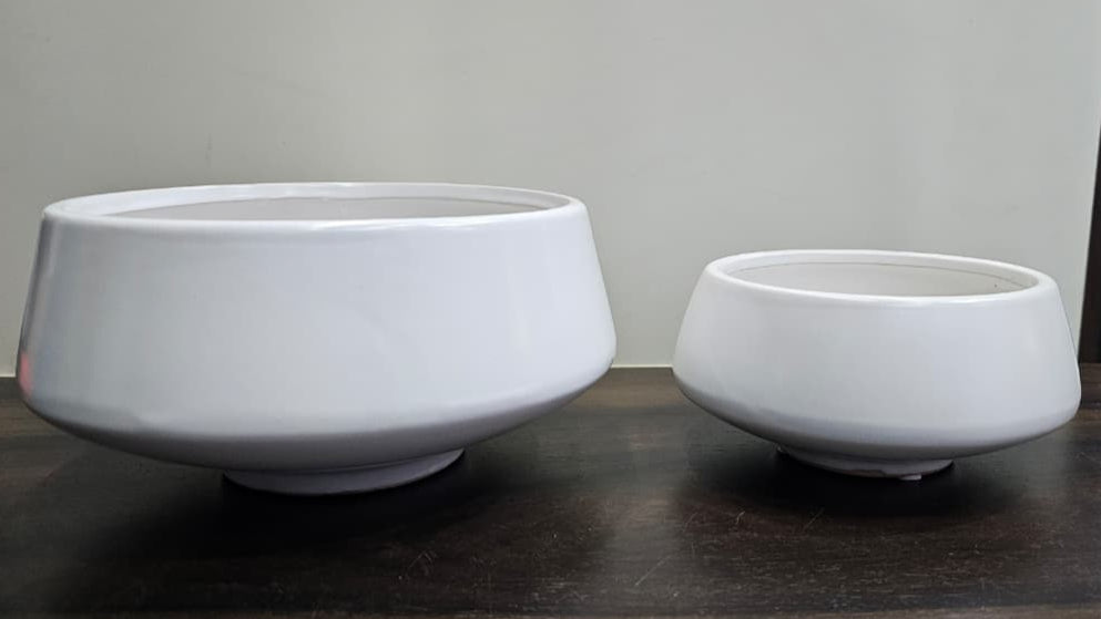 Two white ceramic bowls of different sizes on a dark surface with a light gray background