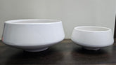 Two white ceramic bowls of different sizes on a dark surface with a light gray background