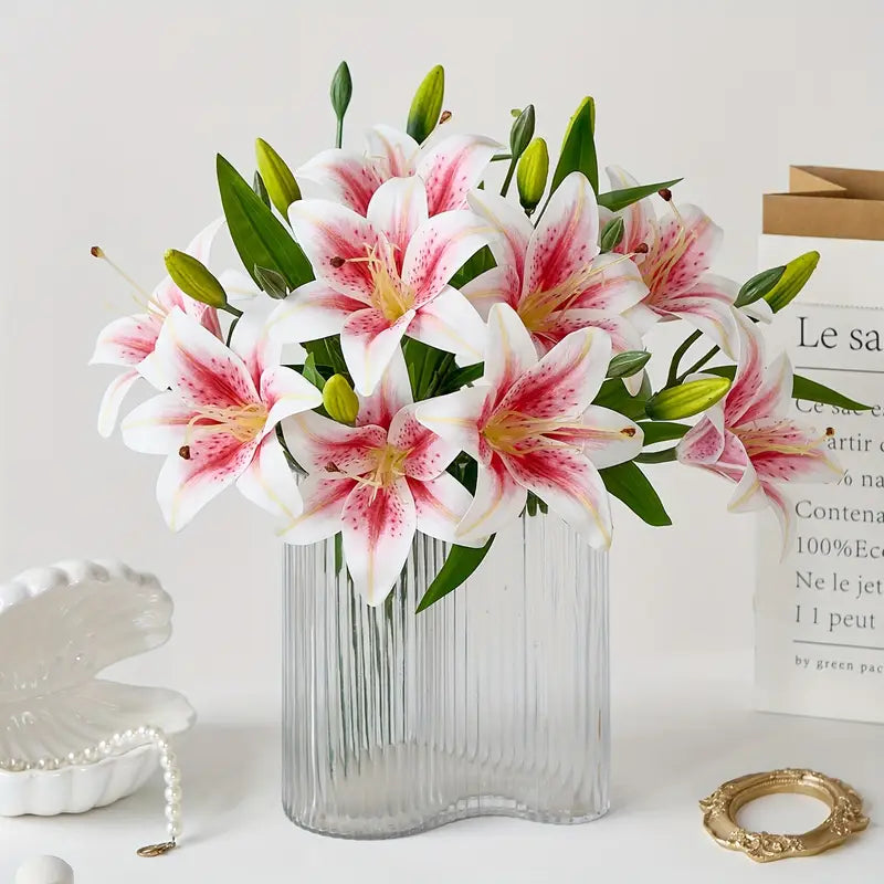 Bouquet of pink and white lilies in a clear vase on a light surface with a white background