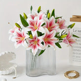 Bouquet of pink and white lilies in a clear vase on a light surface with a white background
