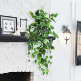 Artificial green vine hanging above a white brick fireplace with decorative items.