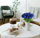 Table setting with a cake, blue tulips in a vase, and Easter eggs in a cozy living room.
