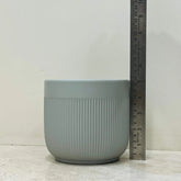 Gray textured pot with a ruler for scale on a light wooden surface.