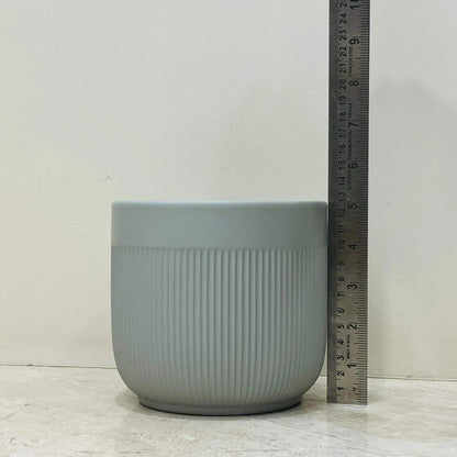 Gray textured pot with a ruler for scale on a light wooden surface.