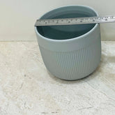 Blue ceramic pot with a measuring tape on a light marble surface