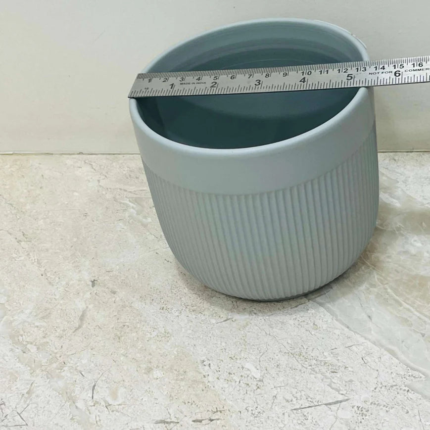 Blue ceramic pot with a measuring tape on a light marble surface