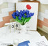 Decorative setup with blue tulips, calendar, and glass on a table.