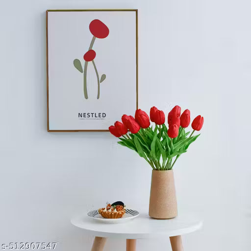 Vase with red tulips on a white table against a light gray wall with a framed picture.